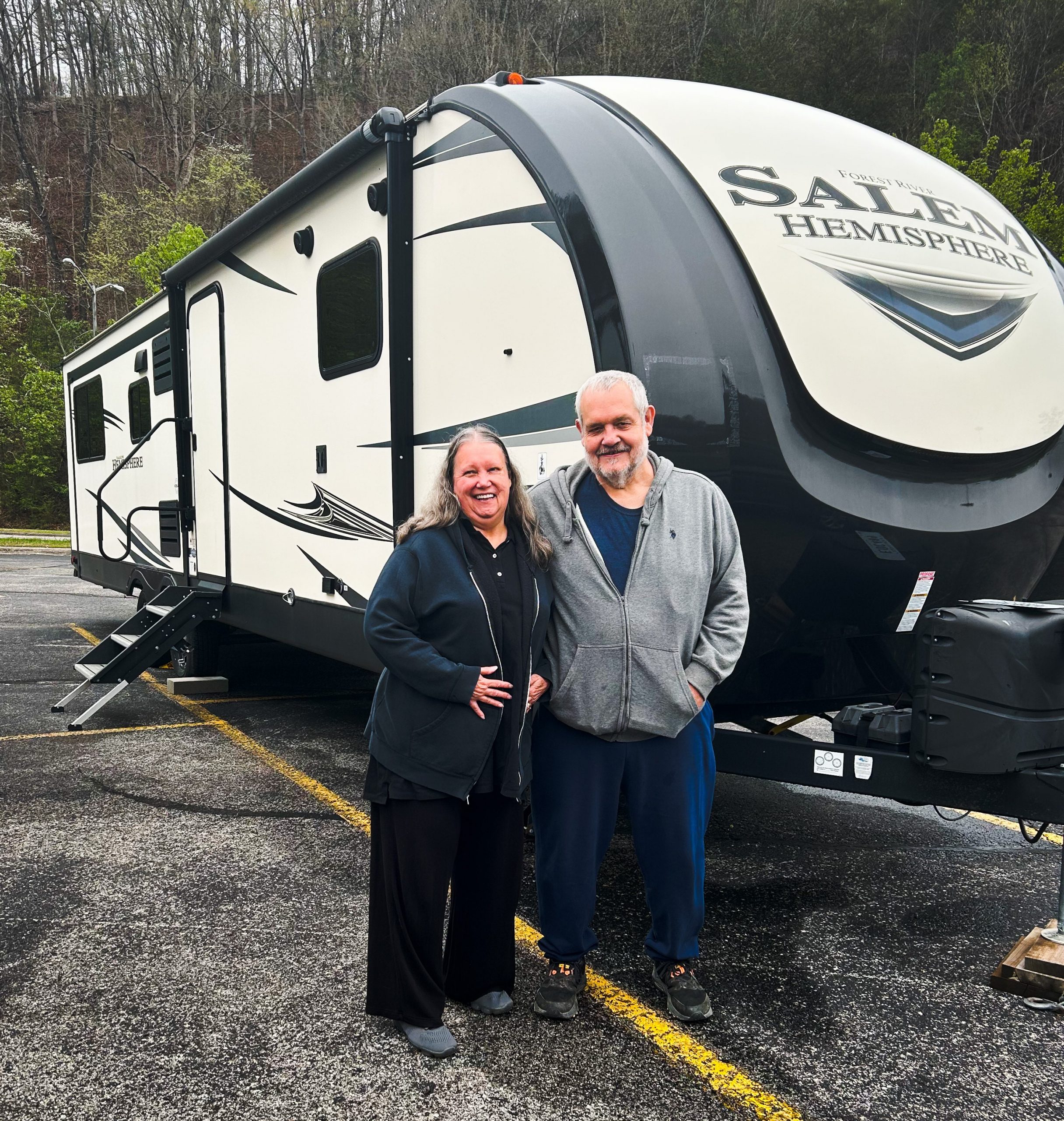 A couple, The Stacys, pose in front of a donated RV.